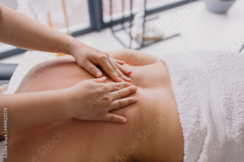 woman is lying on a back massage. Treating muscle pain. masseur kneads the client. Chiropractor at work. Osteopath massages. Relaxation therapy. Shoulders and lower back treatment. Patient in spa