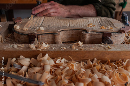 Luthier's hands using gouge to work the wood and make a violin