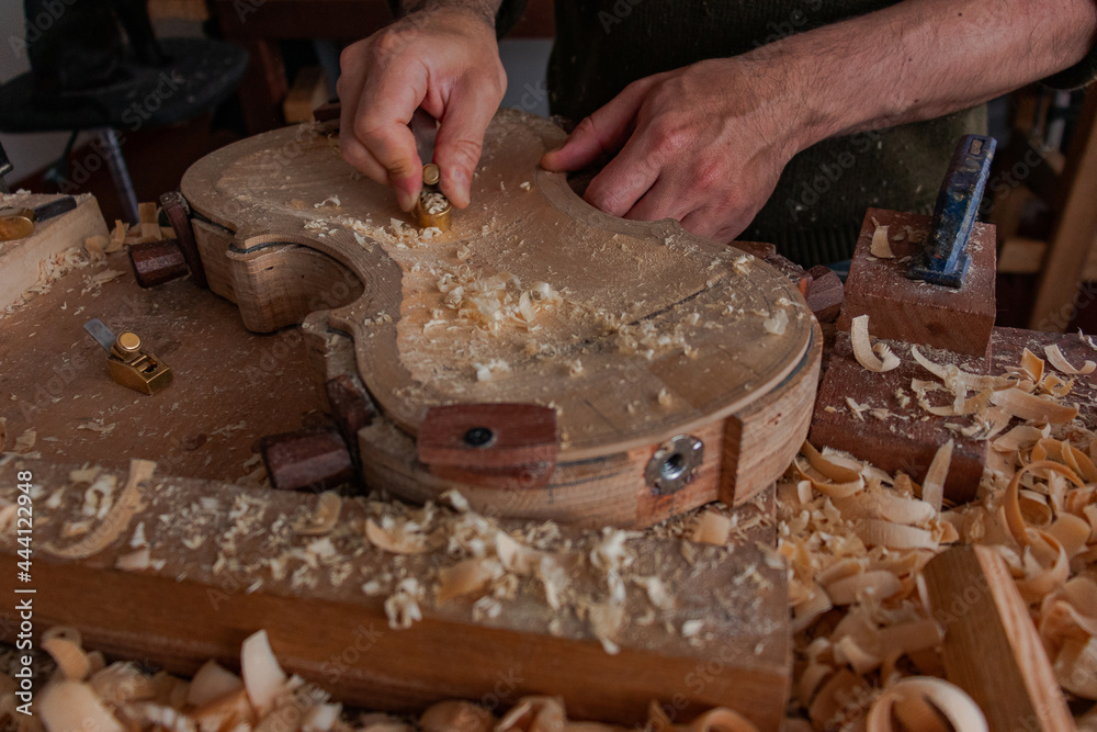 Luthier is using a little tool to give shape the violin body Luthier is using a little tool to give shape the violin body