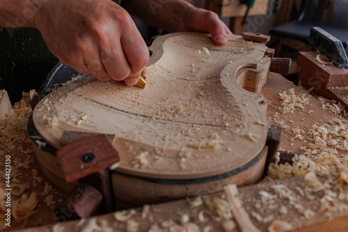Luthier is using a little tool to give shape the violin body  
