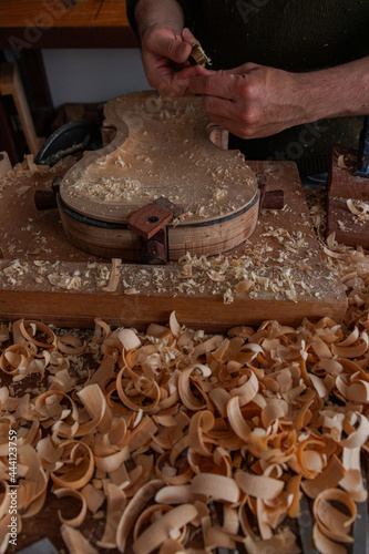 Luthier is using a little tool to give shape the violin body  