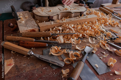Luthier's hands using gouge to work the wood and make a violin