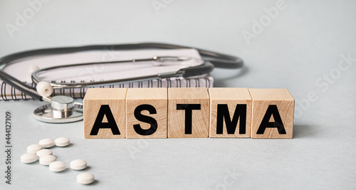 ASTMA inscription on wooden cubes isolated on white background, medicine concept. Nearby on the table are a stethoscope and pills.