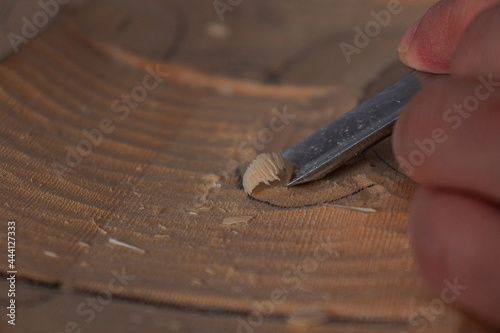 Luthier's hands using gouge to work the wood and make a violin