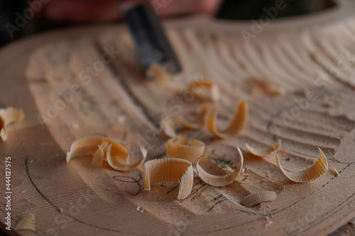 Luthier's hands using gouge to work the wood and make a violin