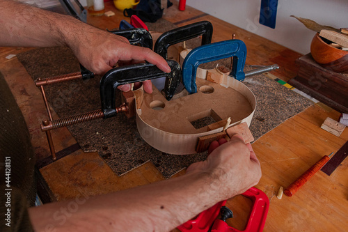 Luthier is using grippers to give shape to violin body
