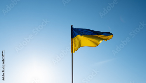 Ukrainian flag waving in wind and sunlight. Flag of Ukraine on blue sky background. photo