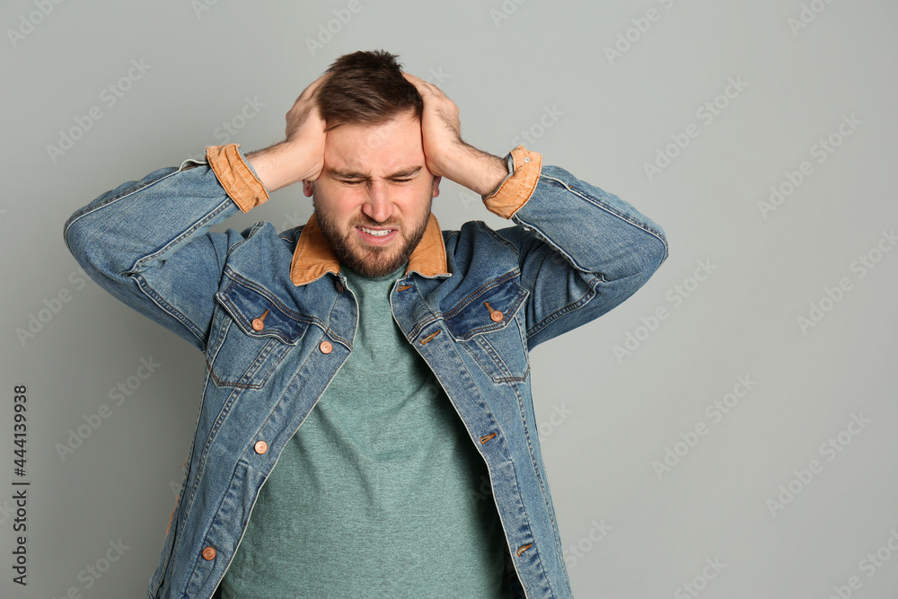 Man suffering from migraine on grey background Man suffering from migraine on grey background