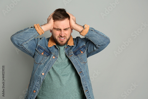 Man suffering from migraine on grey background © New Africa