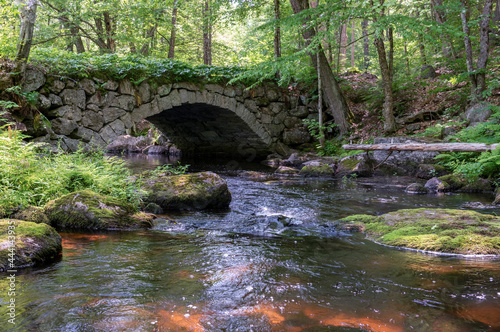 old stone arched bridge in woods with brook stream