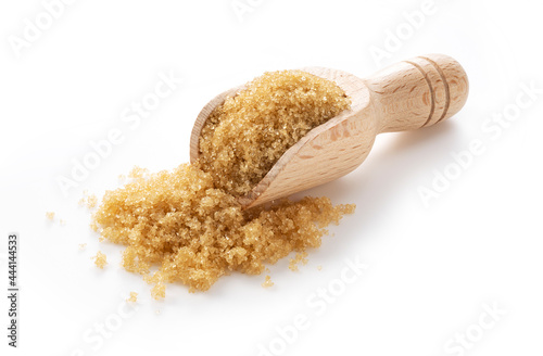 Wooden scoop and brown sugar placed on a white background.