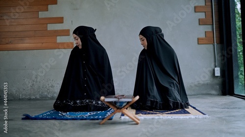 Asian young Muslim woman and sister praying at home