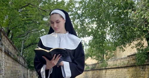 Young nun reading Bible outdoors