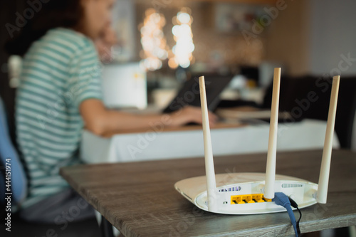 A woman is working at home using a modem router, connecting the Internet to her laptop. photo