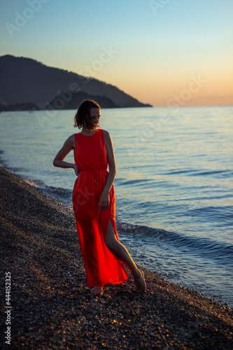 fashionable beautiful girl in red dress standing by the sea