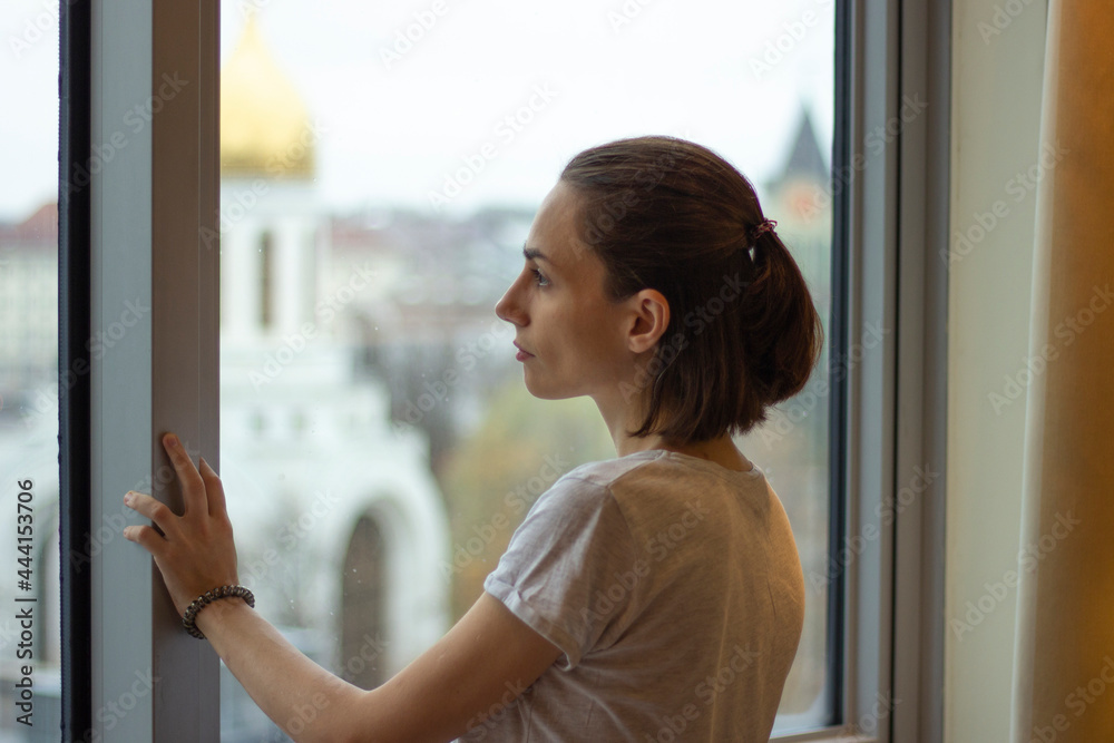 girl standing alone at the window and looking at city view girl standing alone at the window and looking at city view