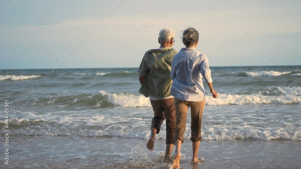 Happy Asian active senior man and woman couple lifestyle running to beach and enjoying funny, Romantic elderly enjoy travel summer vacation, plan life insurance at retirement couple concept