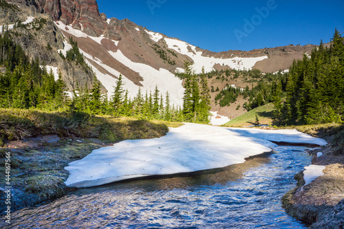 Volcanic mountain with patches of snow melting into streams of water runoff.