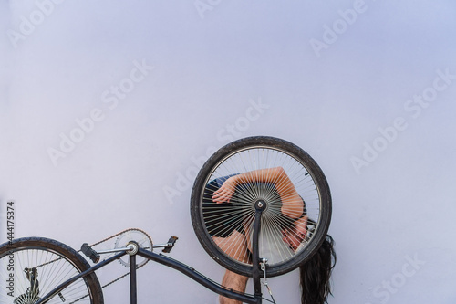 young hispanic latino long-haired man with his upside down bike photo