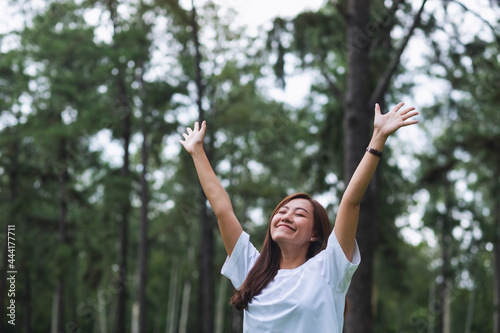 Portrait image of a happy woman with arms rising in the park