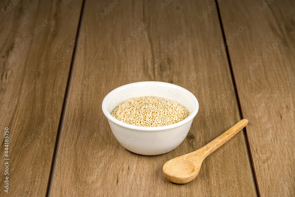 Tazón de cerámica blanca con semilla de quinoa sobre madera