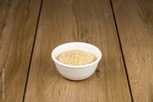 Tazón de cerámica blanca con semilla de quinoa sobre madera