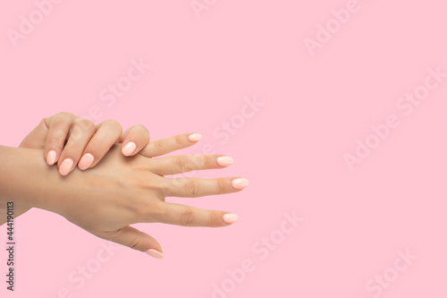 Beautiful female hands with stylish nail manicure gel polish on pink background. top view of groomed female hands with pastel manicure. Top view. copy space
