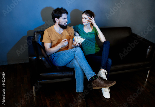 family with popcorn sitting on the couch watching tv movie