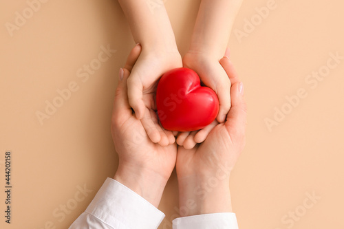 Fototapeta Naklejka Na Ścianę i Meble -  Hands of woman and child with red heart on color background