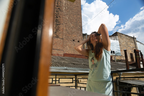 Happy woman in pajamas on the balcony laughing on a summer morning