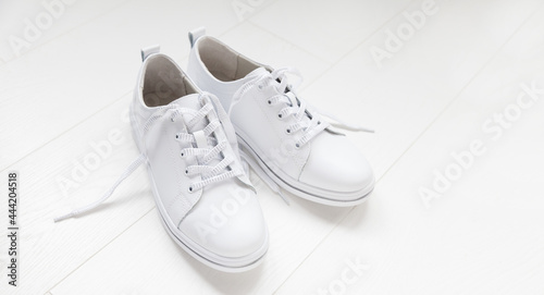 White leather sneakers with laces on white background. banner