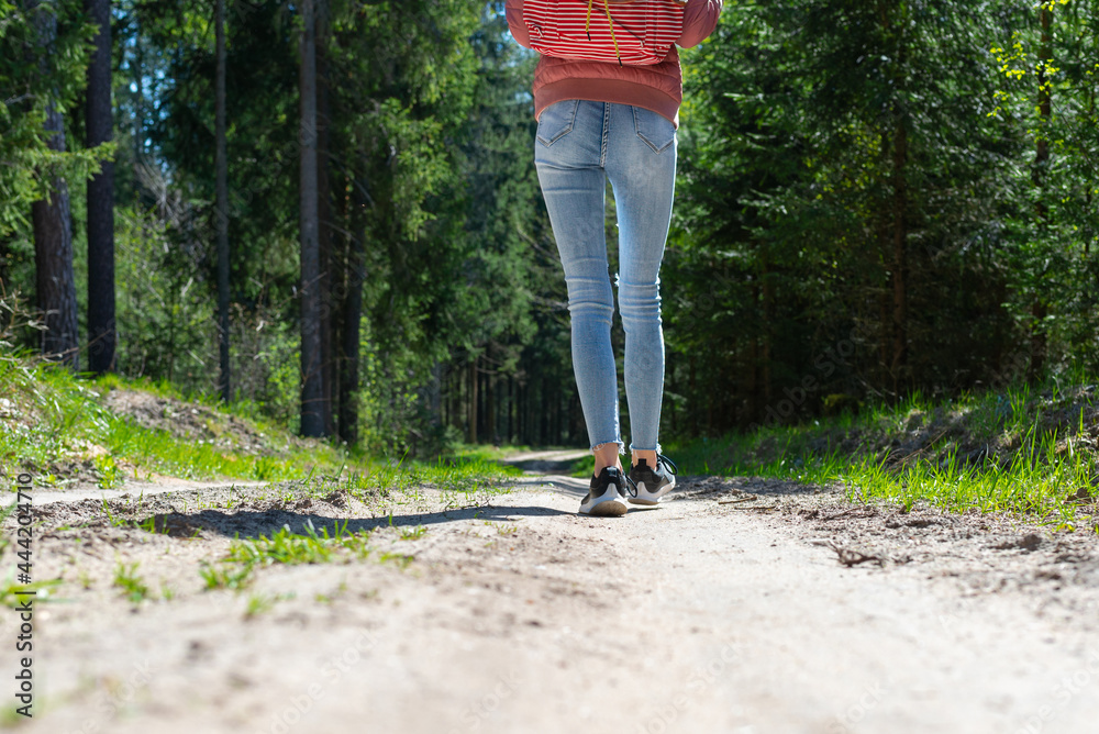 One Girl tourist with a backpack along the road in the woods.Summer warm day.Cropped image.