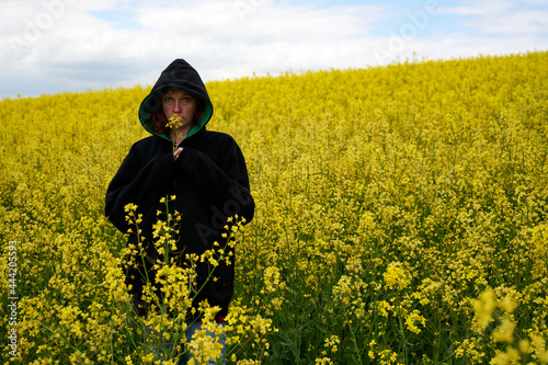 Photo of a woman in a black hood on the background of a rapeseed field