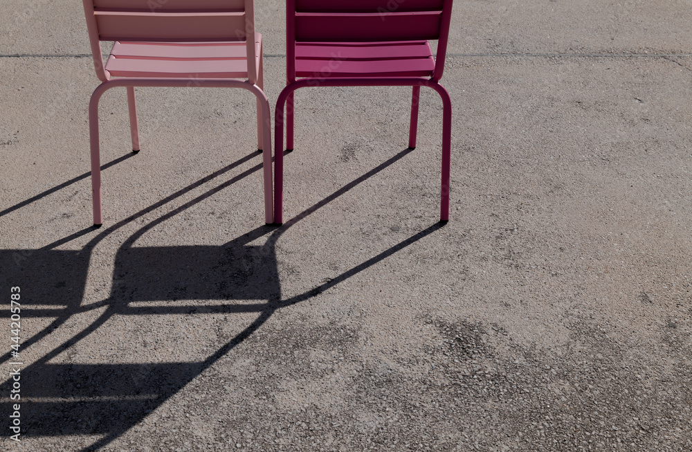 Light and dark pink outdoor chairs and shadow on cement floor Light and dark pink outdoor chairs and shadow on cement floor