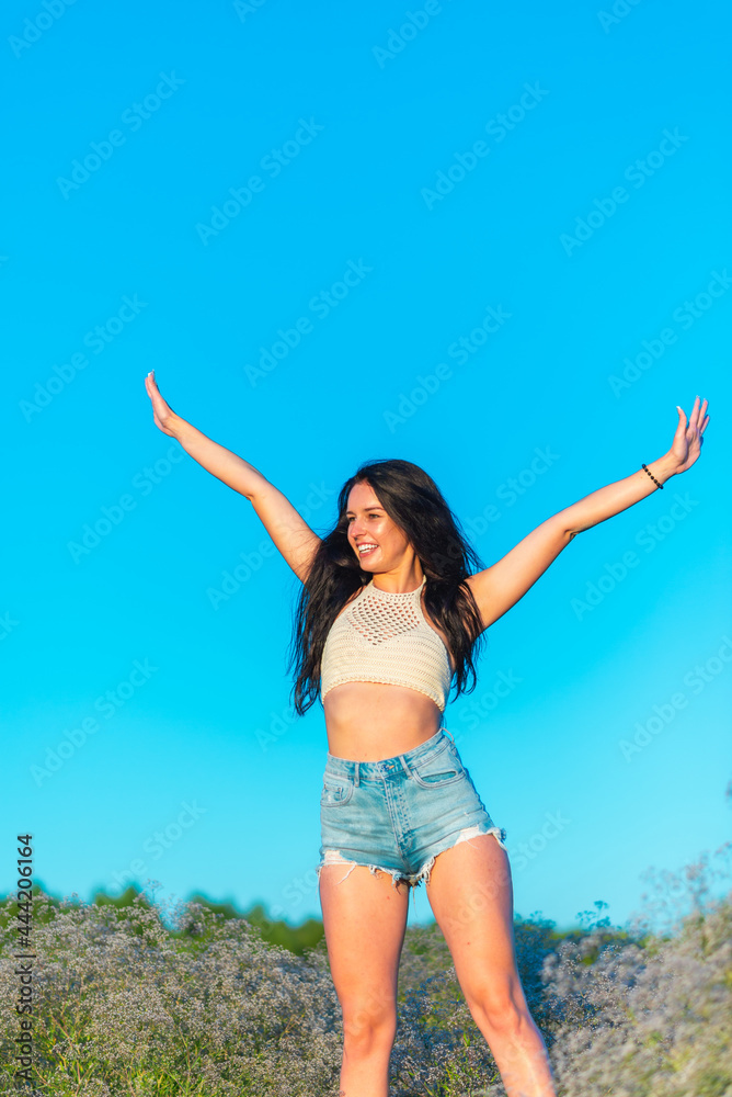 Joyful young girl raised his hands up and smiles. Happiness in lifestyle.woman raising her hands up in the blue air. Joyful young girl raised his hands up and smiles. Happiness in lifestyle.woman raising her hands up in the blue air.