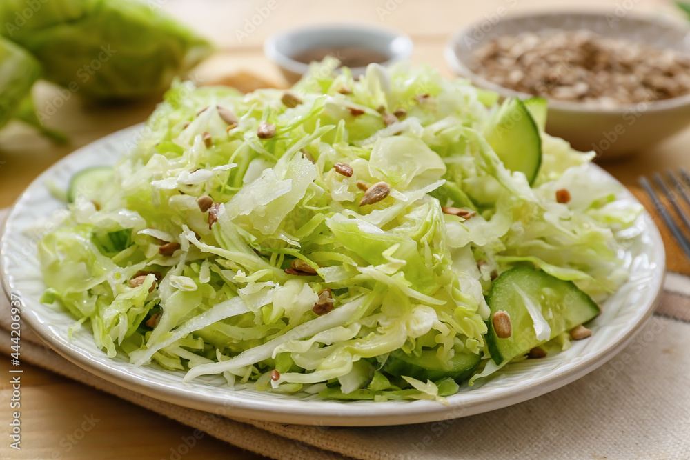 Plate with tasty cabbage salad on wooden table, closeup Plate with tasty cabbage salad on wooden table, closeup