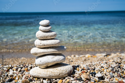 Pebble beach with balancing stone pyramid close-up. Calm and balance concept. Blurred background.