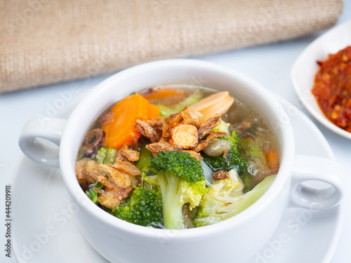 Vegetables soup that contain sausage, broccoli, carrots, etc on a white porcelain bowl