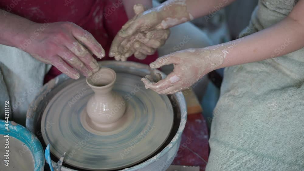 Potter Teaching Pottery Little Girl Man Teaches Child Make Dishes From Clay Work Twisted Potters Wheel. Master Crock. Close up only hands Potter Teaching Pottery Little Girl Man Teaches Child Make Dishes From Clay Work Twisted Potters Wheel. Master Crock. Close up only hands