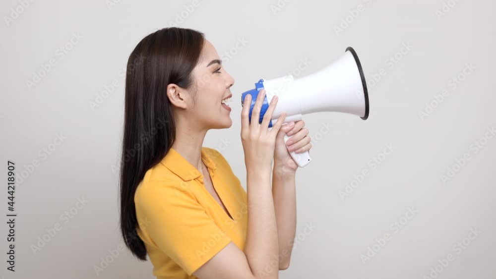 Shout out loud with megaphone. Young beautiful asian woman woman announces with a voice about promotions and advertisements for products at a discounted price. Shopping and fashion concept. Shout out loud with megaphone. Young beautiful asian woman woman announces with a voice about promotions and advertisements for products at a discounted price. Shopping and fashion concept.