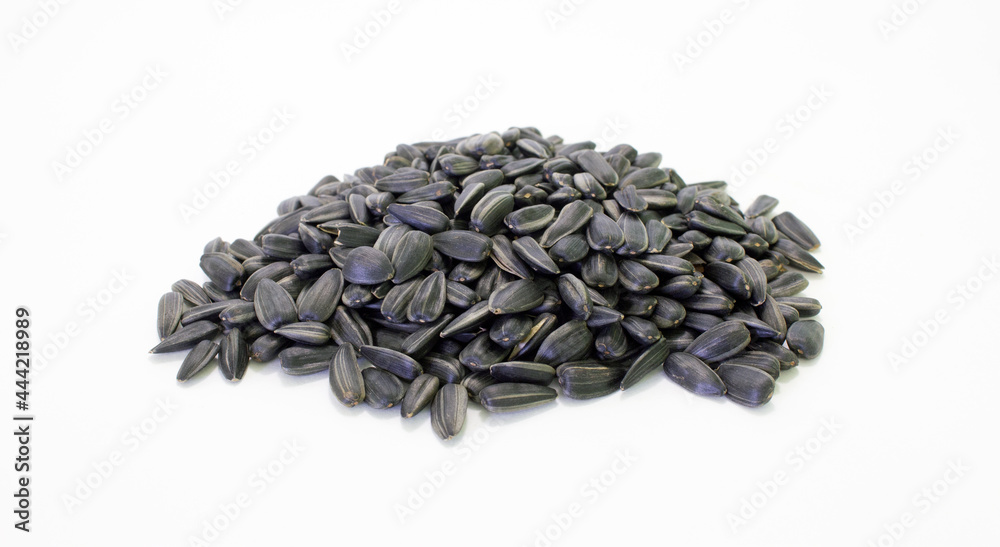 A heap of sunflower black seeds with shell on white background. Agriculture harvest time. Source for vegetable oil production. A heap of sunflower black seeds with shell on white background. Agriculture harvest time. Source for vegetable oil production.