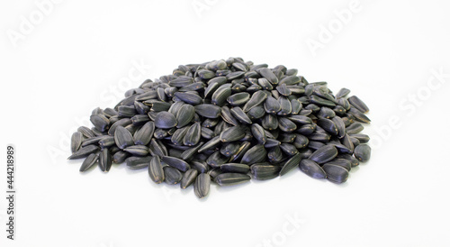 A heap of sunflower black seeds with shell on white background. Agriculture harvest time. Source for vegetable oil production.