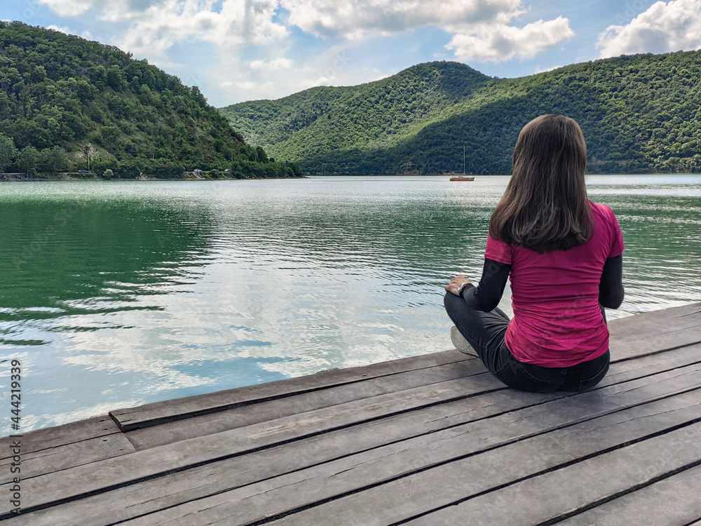 Woman sitting on wooden floor and looking at water. Abrau-Durso lake