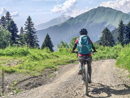 Back view of active woman riding mountain bike on road