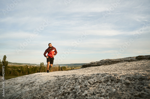 Young muscular male athlete running up the hill
