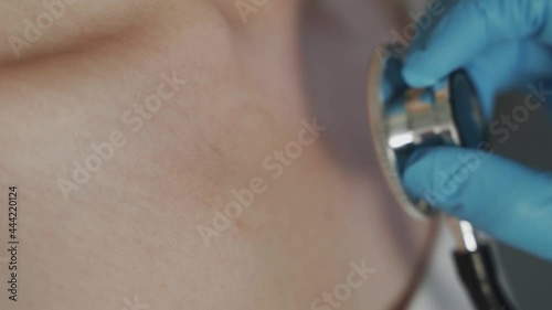 The doctor's hand in medical gloves holds a stethoscope and examines the patient. At a therapist's appointment. Pneumonia and other lung diseases. Close-up, 4K UHD.