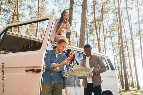 Using map. Group of young people is traveling together in the forest at daytime photo