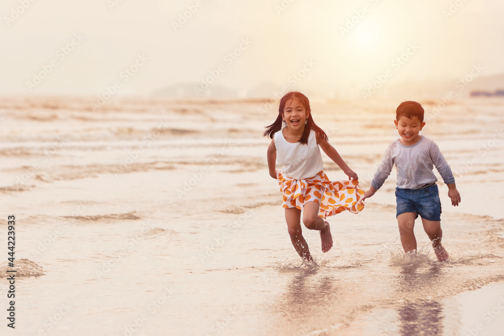 Image of happy asian family children girl and boy running or playing together on sunrise beach during happy day