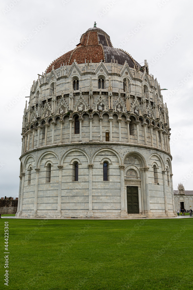 View to the baptistery near leaning Tower and cathedral of Pisa, located on Piazza dei Miracoli (Square of Miracles)