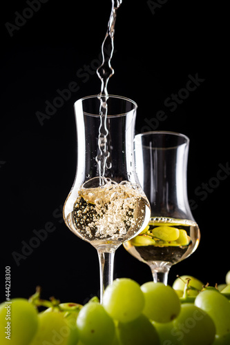 Pouring Italian golden grappa into a glass on black background